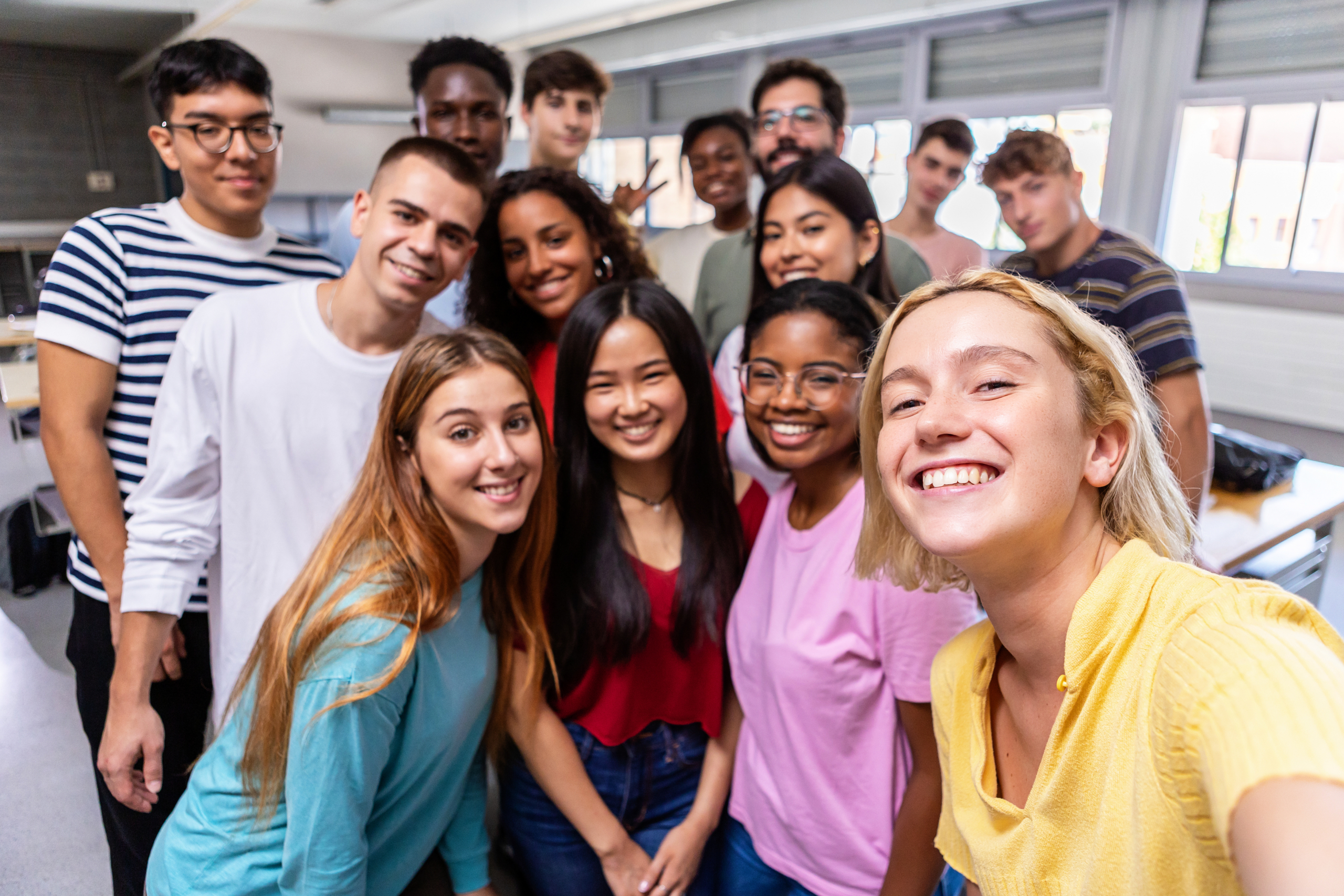 Diverse big group of learners taking selfie with teacher in school setting