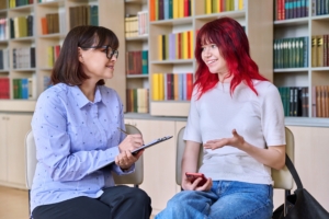 college and career advising counselor counseling teenage student in library with books in the background 