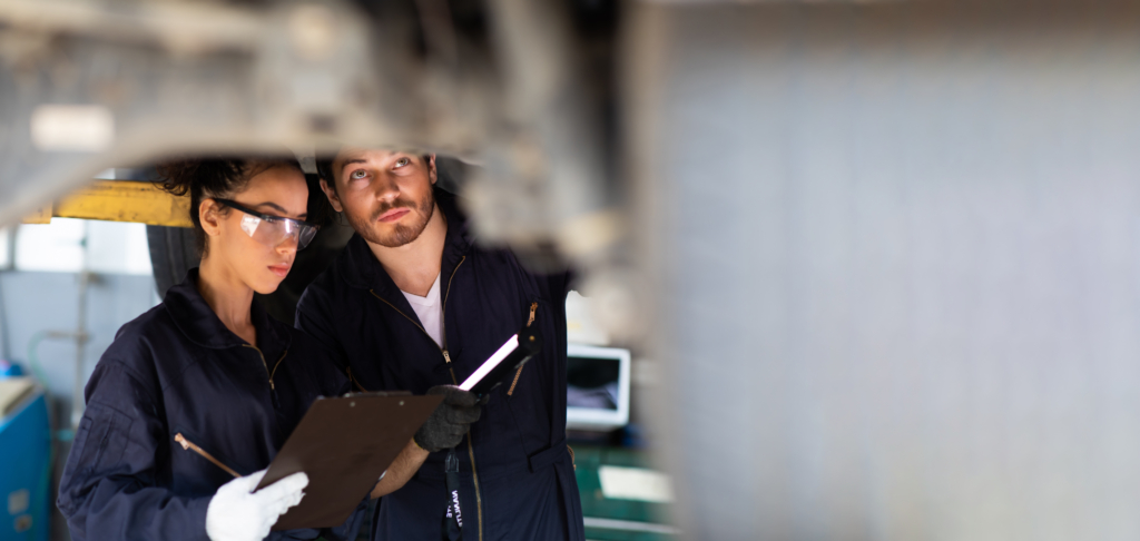 Hispanic Female trainee Mechanics Working Underneath Car Together Car maintenance and auto service garage. Car maintenance and auto service garage concept.